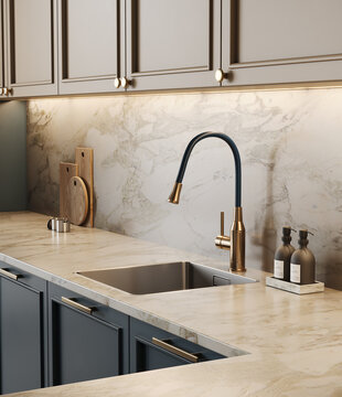 Close-up view of kitchen faucet, blue and beige kitchen fronts, sink, decor on marble countertop. Modern luxury with gold decor elements in kitchen