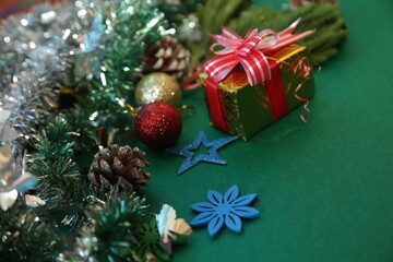 Season's greetings scene.Share your warm wishes with this image idea.view of magnificent giftbox with ribbon, sparkling ornaments, frosty fir, ball, cone on green backdrop, ready for personalized ad
