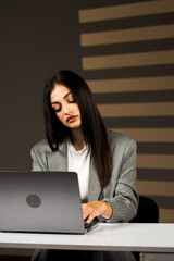 Young Business Woman Focused on Her Laptop in a Modern Office Environment Highlights the Essence of Remote Work and Productivity