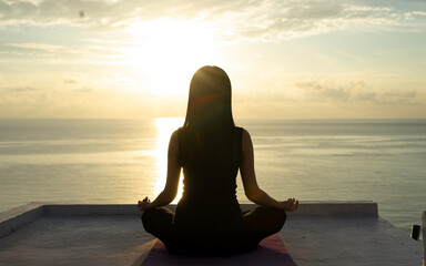 silhouette of a woman meditating on the beach