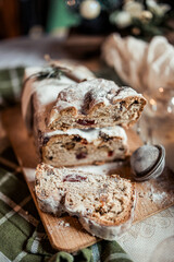 Christmas stollen decorated with a cinnamon stick on a festive table, Scandinavian style, Scandinavian Christmas, stollen with powdered sugar, raisins, candied fruits
