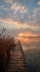Obraz premium A serene lake scene with a boardwalk, misty waters, and sun setting/rising. Tranquil atmosphere, orange glow, reeds, picturesque beauty.