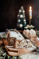 Christmas stollen decorated with a cinnamon stick on a festive table, Scandinavian style, Scandinavian Christmas, stollen with powdered sugar, raisins, candied fruits