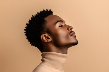 Obraz premium side profile of a black man with chiseled jawline, short curly hair, and turtleneck sweater in a neutral background