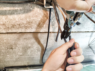 A technician working diligently to repair electrical wires in a basement, ensuring safety and...