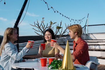 Joyful Outdoor Party with Friends Celebrating Under Blue Sky with Red Cups and Festive Decorations on a Sunny Day
