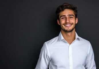 Smiling young man in white shirt against dark background, conveying confidence and happiness with natural charm and engaging personality perfect for various projects