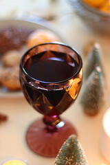 Various Christmas decorations, cookies, chocolate, nuts and tangerines, wine glasses and lit candles on the table. Holiday hygge at home. Selective focus.