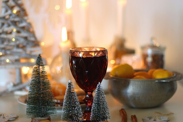 Various Christmas decorations, cookies, chocolate, nuts and tangerines, wine glasses and lit candles on the table. Holiday hygge at home. Selective focus.