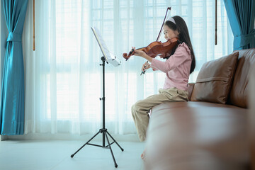 A girl violinist plays and practices the violin at home © Wosunan