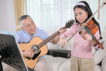 A girl violinist and her grandfather practice music together at home