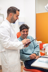 Dentist showing information on tablet to patient in dental clinic