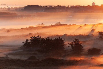 Beautiful sunrise at Lighthouse of Rubjerg Knude. Denmark north coast with wonderfully illuminated fog.