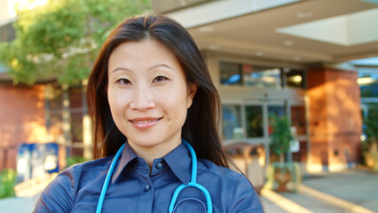 Portrait Of Female Doctor With Stethoscope At Work Standing Outside Modern Hospital