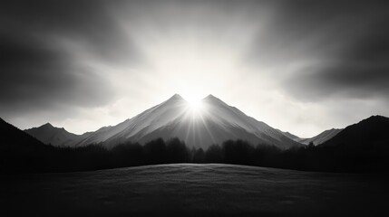 Fototapeta premium A dramatic black-and-white image of mountains with a radiant sun emerging from behind, casting powerful rays through the clouds.