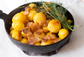Young potatoes with pork belly fried in frying pan