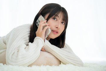 うつ伏せで電話をかける女性