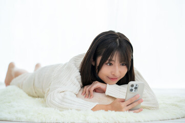 うつ伏せに寝てスマホを操作する女性