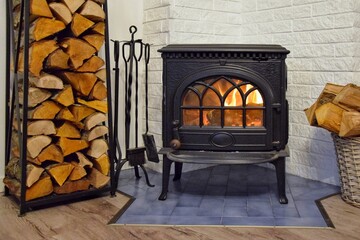 Firewood near the burning fireplace. It is warm in the house.