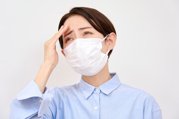 風邪マスクを付けて頭痛がする女性　白背景