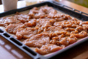 Fried chicken fillet with pineapple and cheese on a dark baking sheet