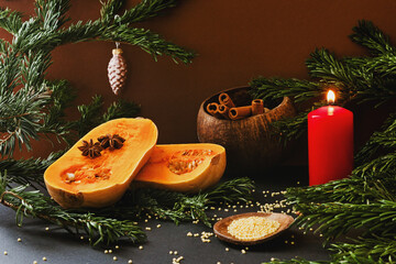 Sliced elongated pumpkin on a festive Christmas table with a lit candle, pine branches, millet, and...