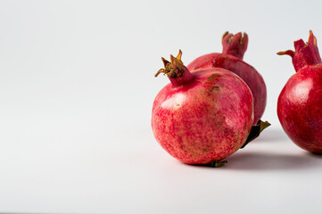 Ripe pomegranate fruits with leaves on a light background, horizontal.