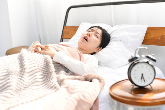 ベッドの上でいびきをかき寝るアジア人女性