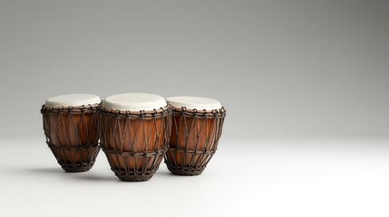 Three wooden drums with white tops sit on a minimalist surface, showcasing their natural texture and craftsmanship against a neutral background.