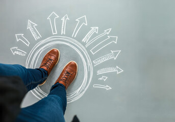 Creative direction symbolized by feet standing on an arrow circle in a modern workspace
