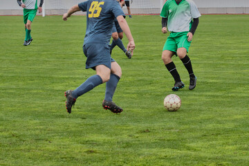 attacking soccer player in a blue uniform is preparing to pass the ball forward, game tactics in football, footballer with the ball on the green football field close-up.