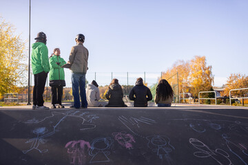 Social volunteers talking with skateboarder by chalk drawings on ramp