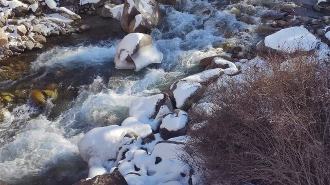  cold mountain river with ice and snoe in Kyrgyzstan