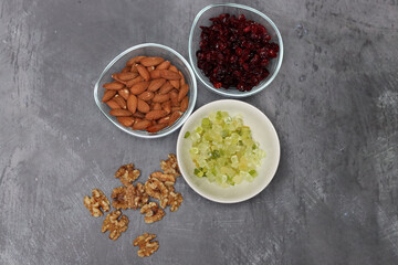 Ingredients for making cookies on a table. Top view photo of raisins, nuts and dried cranberries on a gray background with space for text. Healthy eating concept. 