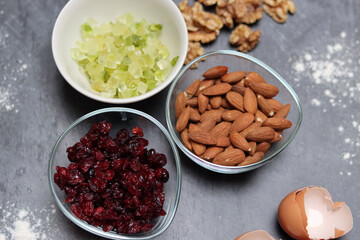 Ingredients for making cookies on a table. Top view photo of raisins, nuts and dried cranberries on a gray background with space for text. Healthy eating concept. 