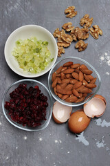 Ingredients for making cookies on a table. Top view photo of raisins, nuts and dried cranberries on a gray background with space for text. Healthy eating concept. 