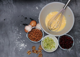 Ingredients for making cranberry pie - eggs, flour, sugar, nuts, raisins on a gray background