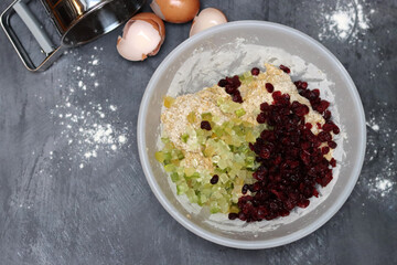 Ingredients for making cranberry pie - eggs, flour, sugar, nuts, raisins on a gray background