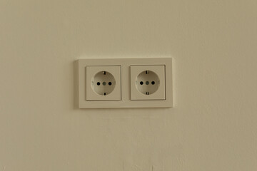 Two white electrical outlets on a cream wall