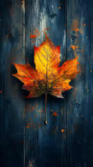 Obraz premium A vibrant autumn leaf on a textured wooden background, showcasing seasonal beauty.