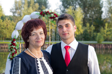 portrait of the groom with his mother at a wedding in the park on a summer day