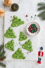 Christmas shortbread cookies in shape of Christmas tree with decoration on light wooden background. Idea for New Years recipe. Traditional sweet Christmas treats for children and adults.