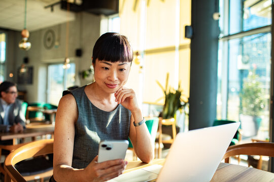 Businesswoman checking phone while working at a caf?