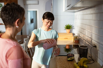 Lesbian couple making healthy organic smoothie together in modern kitchen