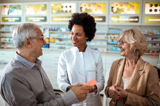 Pharmacist assisting senior couple with medication choice in pharmacy