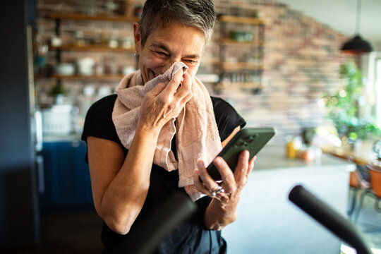 Senior woman using smartphone after workout at home