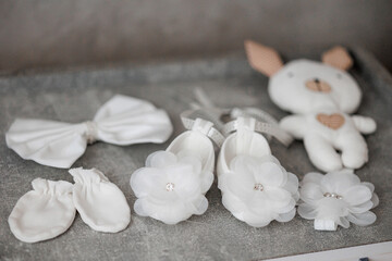 A collection of baby items including a pair of white shoes, a pair of white gloves, and a white stuffed animal