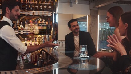 Smart bartender with VIP customer at luxurious bar greeting new beautiful guest at counter in engaging lively conversation at back view in lighting atmosphere at lighting warm nightclub. Vinosity.