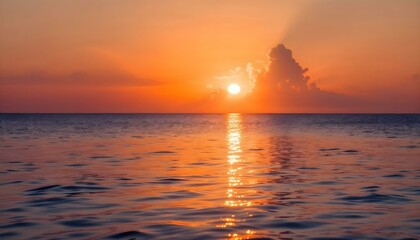 Naklejka premium A breathtaking ocean sunset with the sun low on the horizon, casting warm hues of orange and gold across the sky