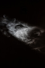 Cigarette smoke in a trickle of light.
